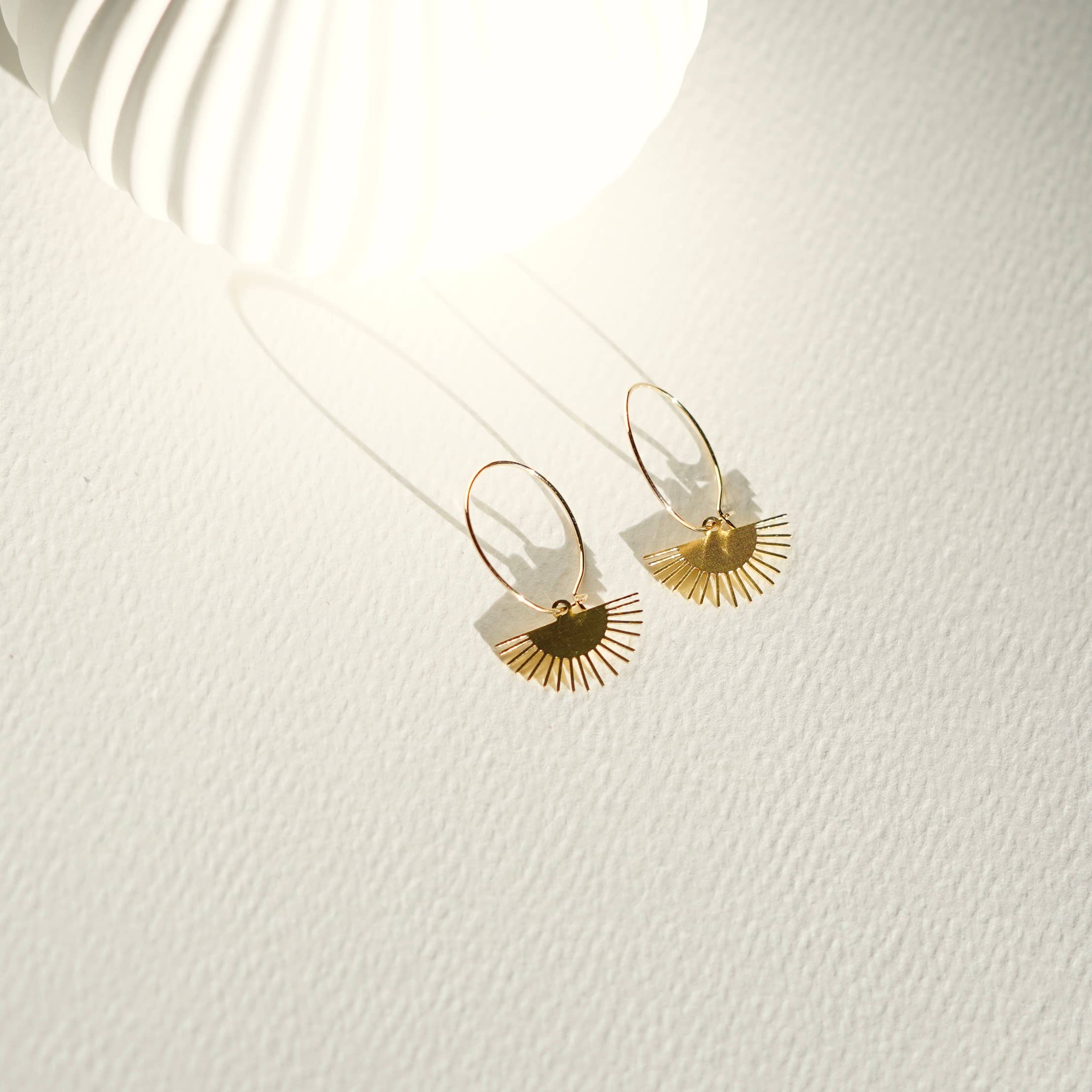 Gold earrings on a white textured surface