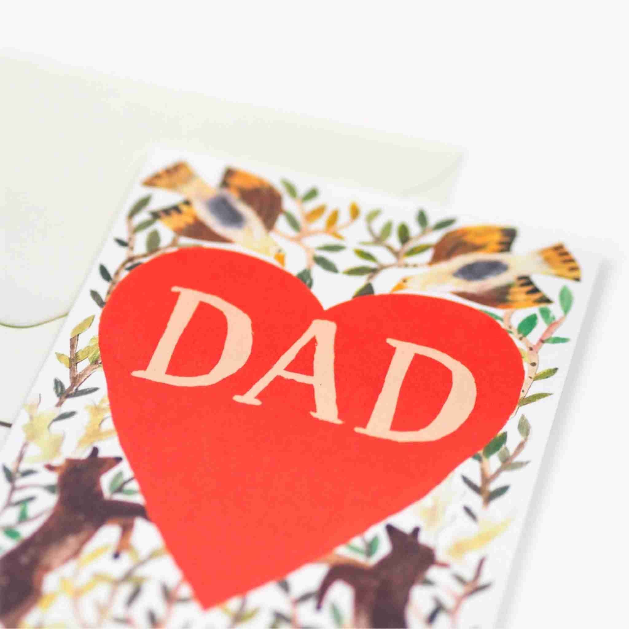 Card with a red heart and 'DAD' text on a nature-themed background
