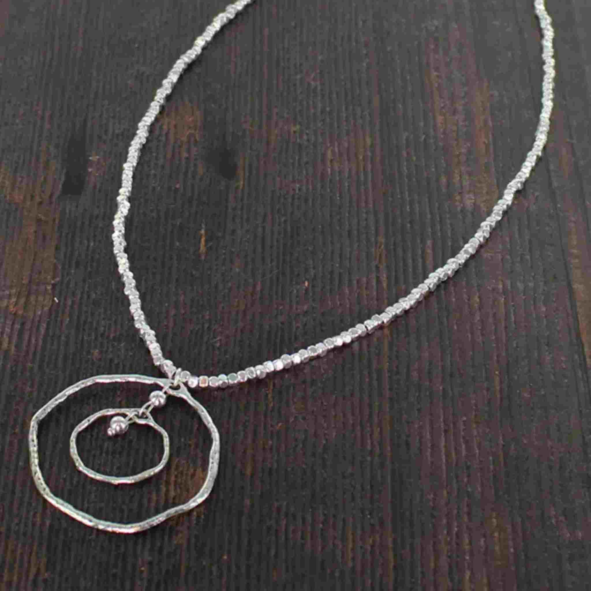 Silver necklace with a unique pendant on a dark textured surface