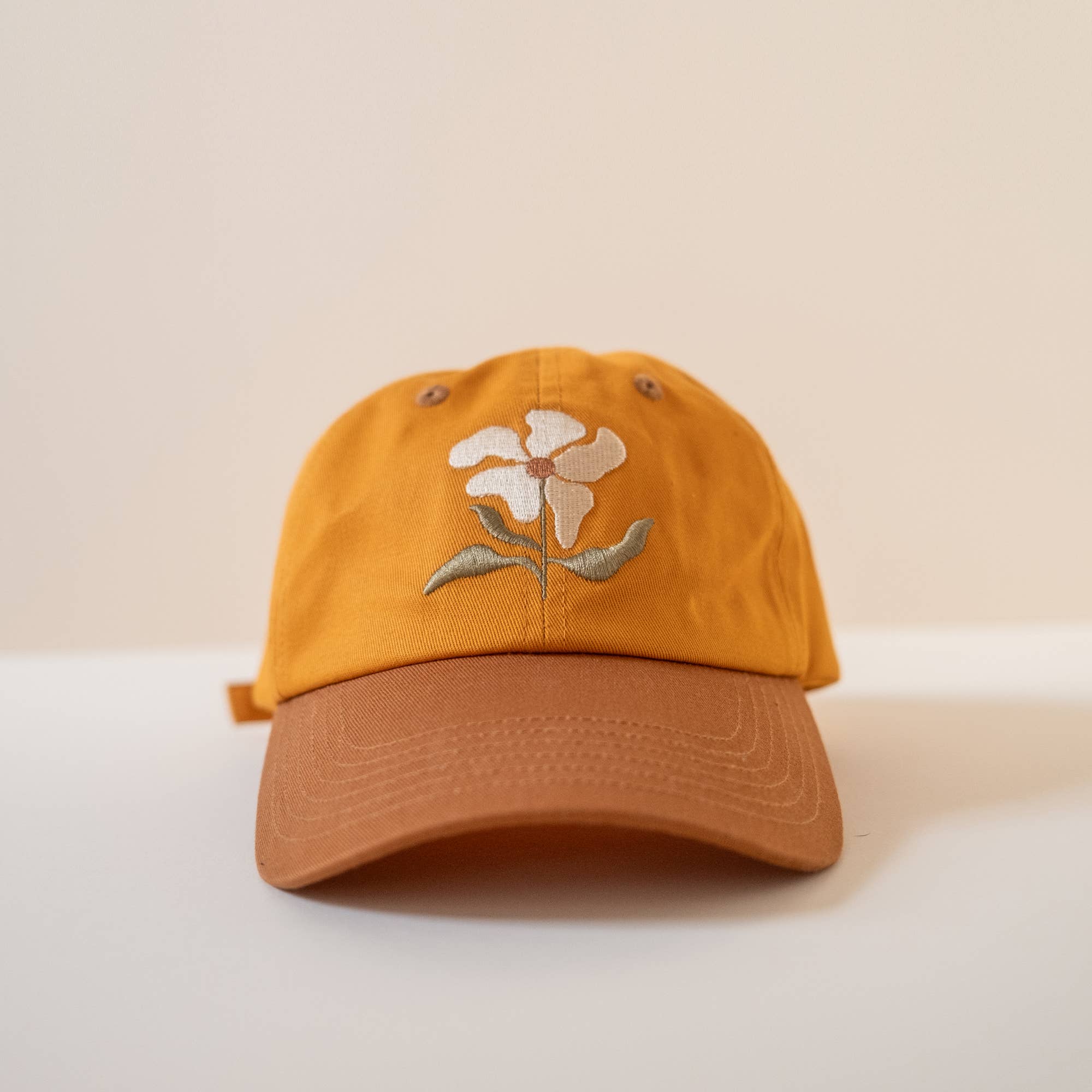 Yellow cap with floral embroidery on a beige background