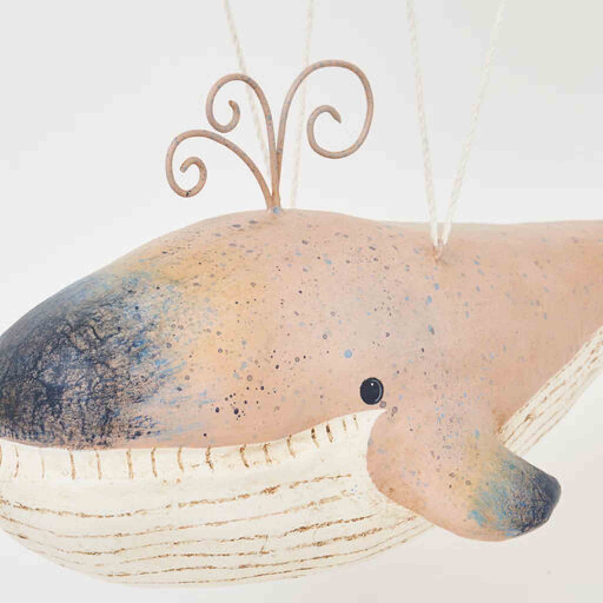Decorative whale ornament with a speckled pattern on a white background