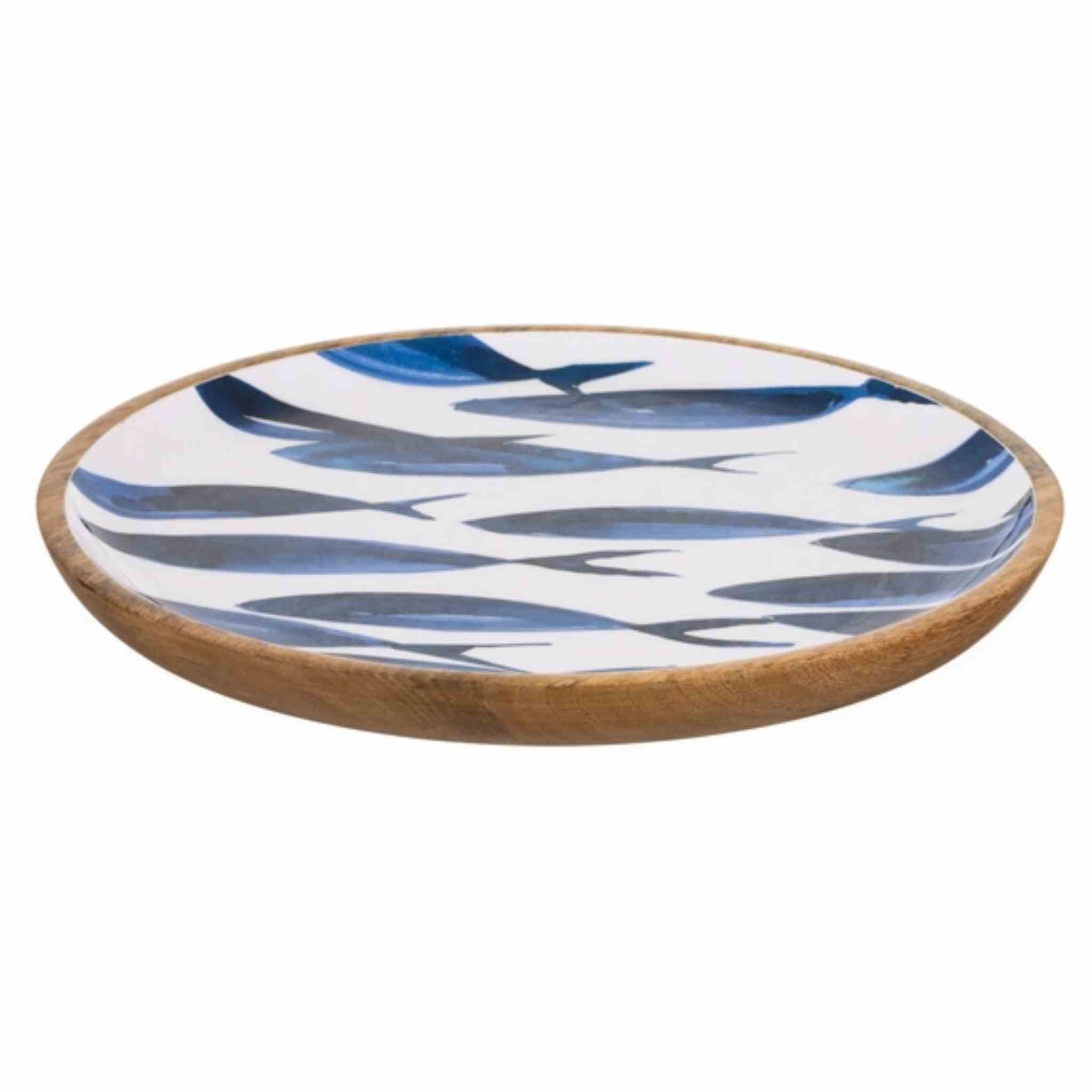 A round wooden serving platter with a white glazed interior decorated with a pattern of blue and gray fish