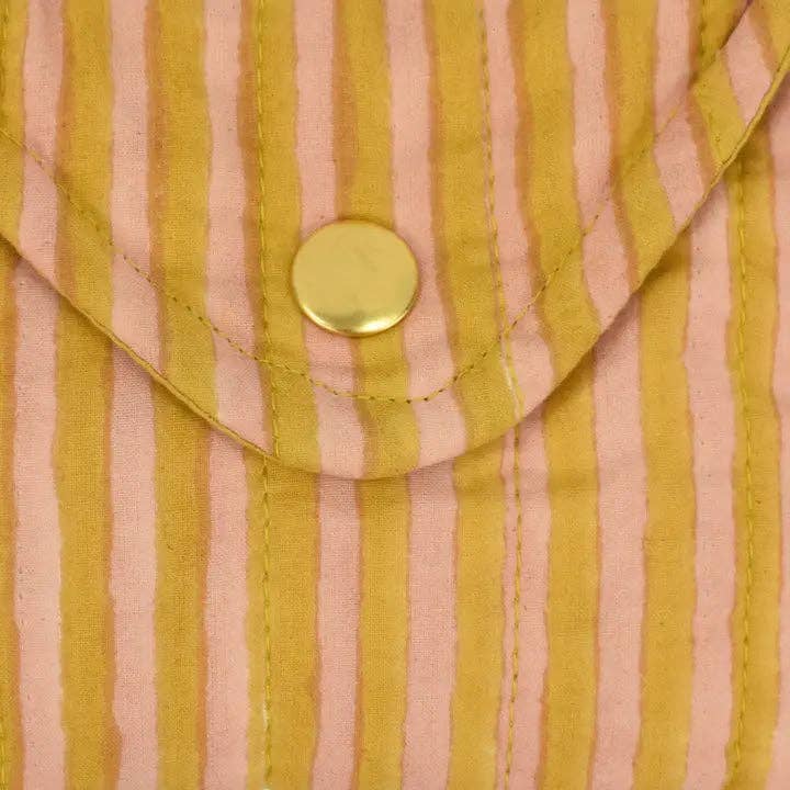 Close-up of a pink and yellow striped fabric with a gold button.