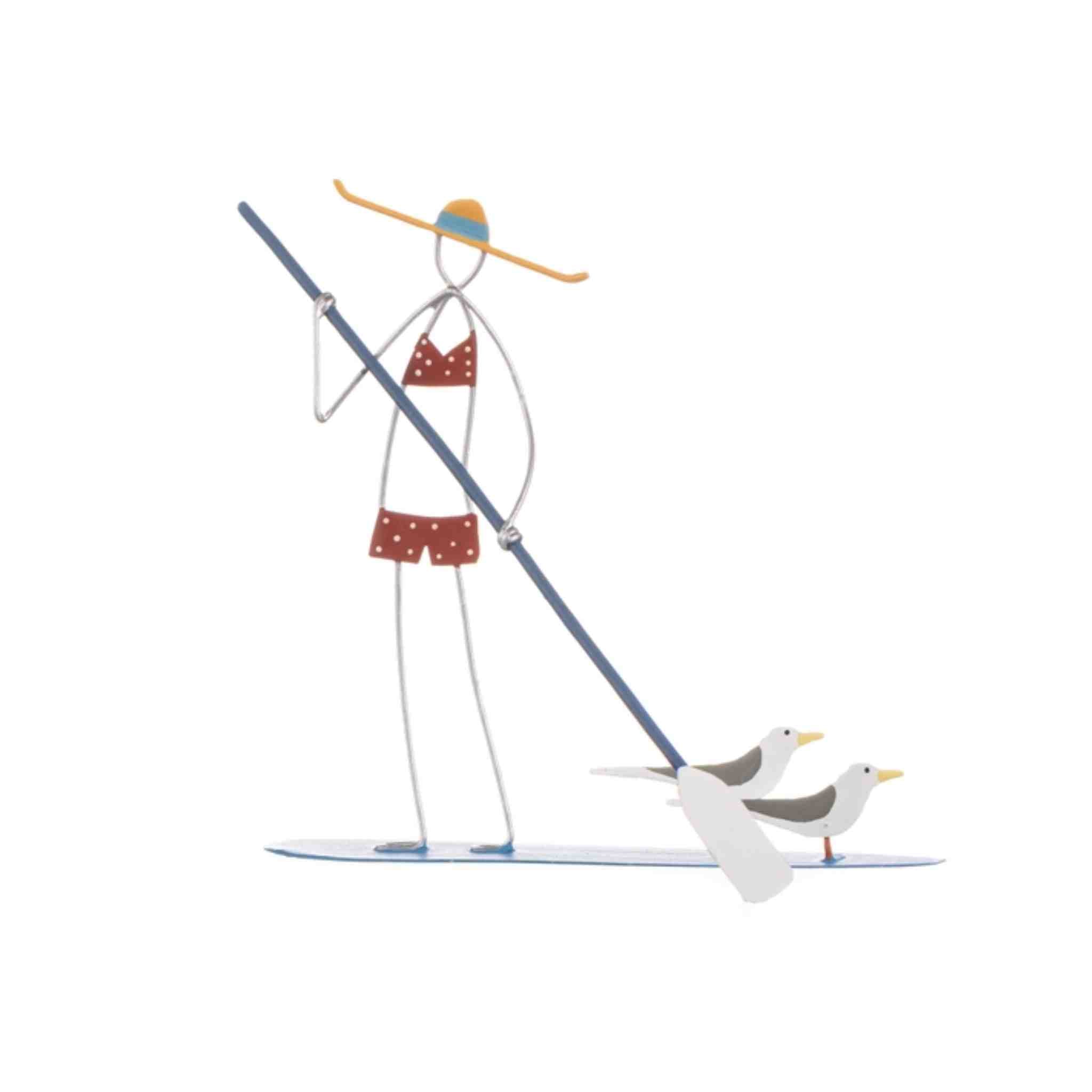 A minimalist metal cutout sculpture of a woman in a red polka-dot bikini standing on a paddleboard with two seagulls, isolated on a white background.