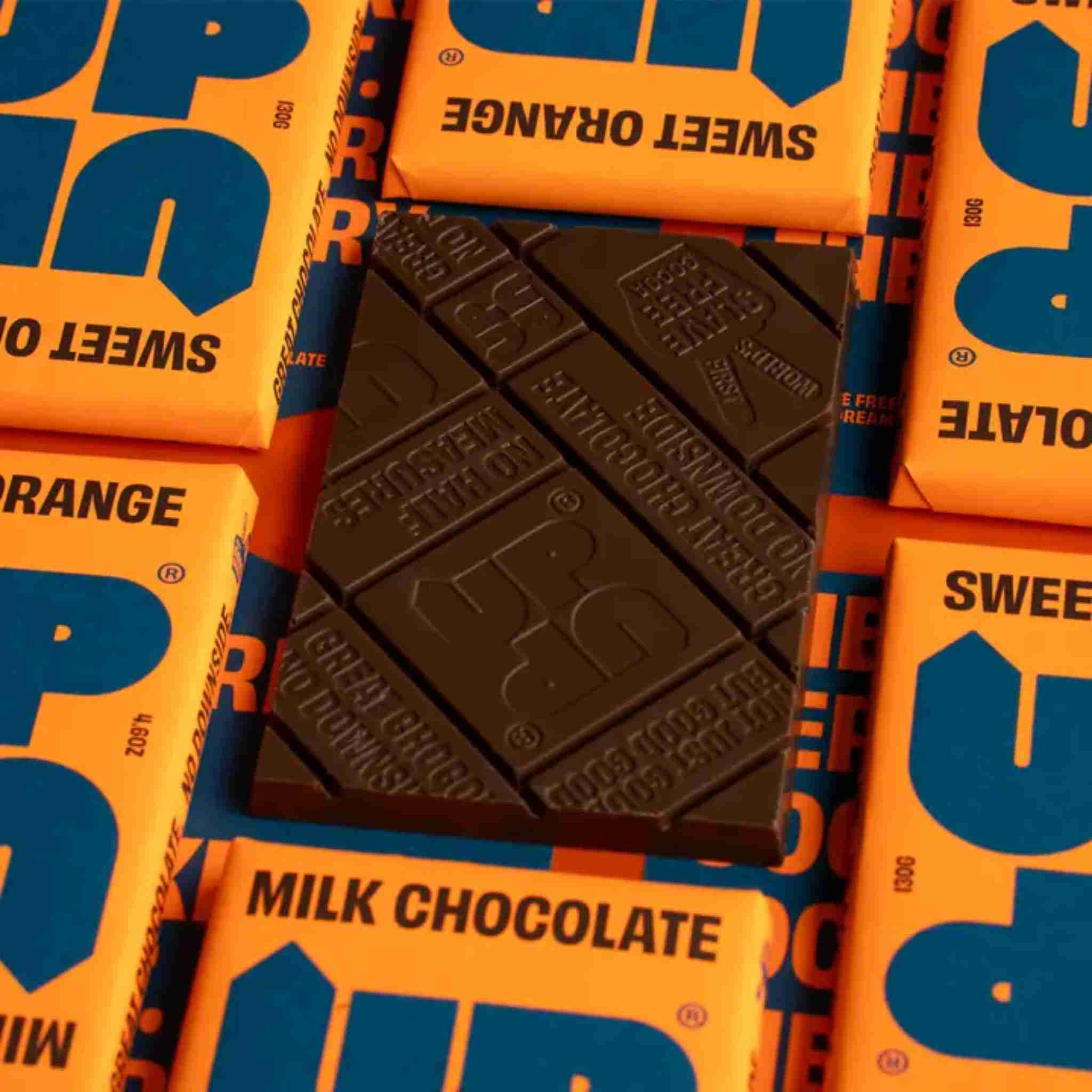 Dark chocolate bar on top of 'Sweet Orange' chocolate bars with orange packaging.