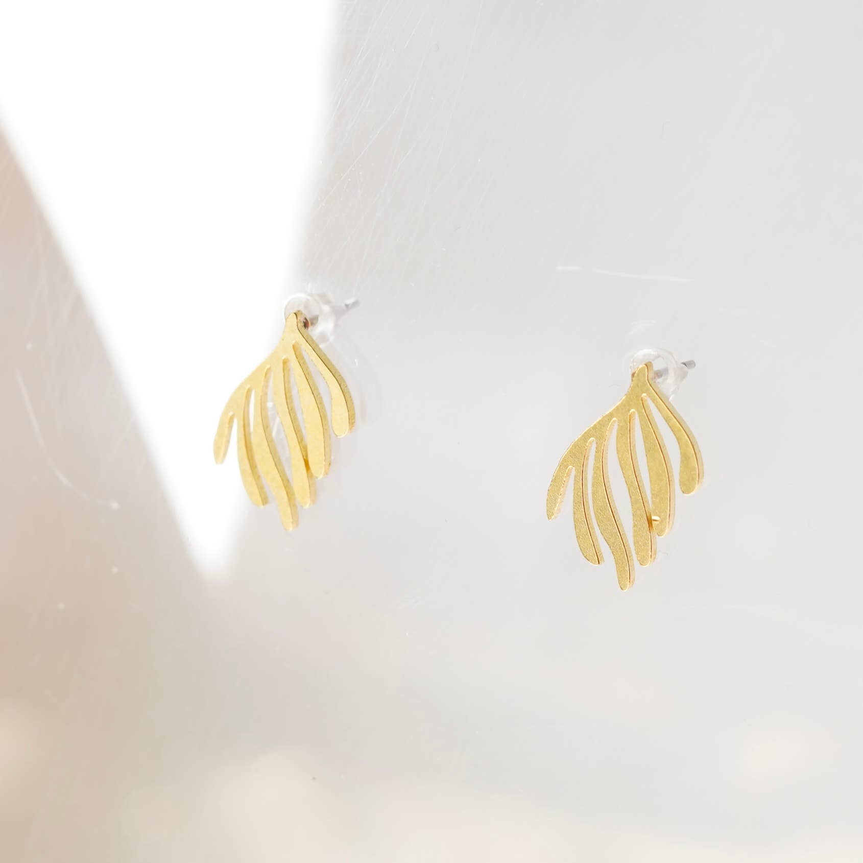 Gold leaf-shaped earrings on a white background