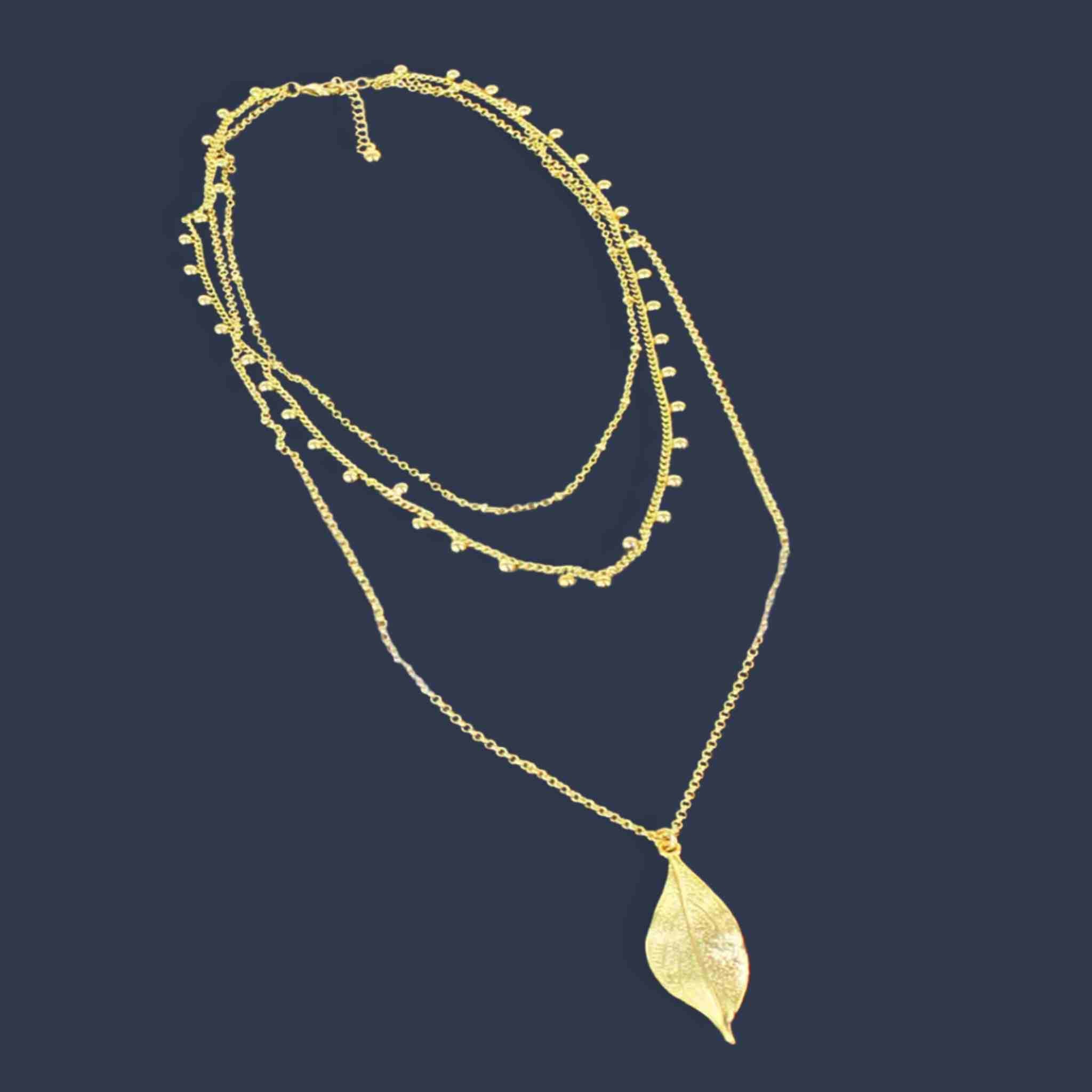 Gold necklace with leaf pendant on a dark background