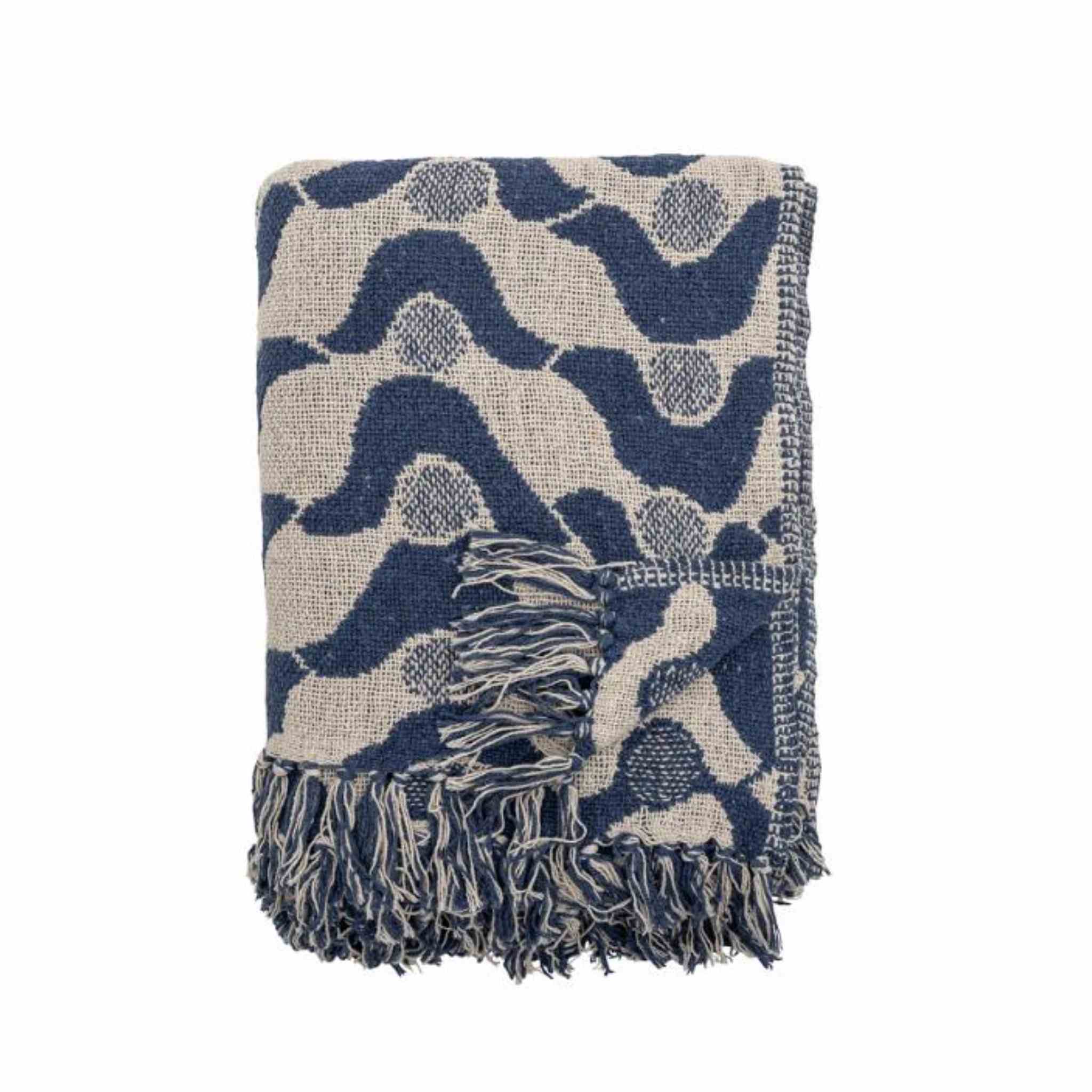 A folded woven throw blanket with a navy blue and beige abstract wavy pattern and fringed edges