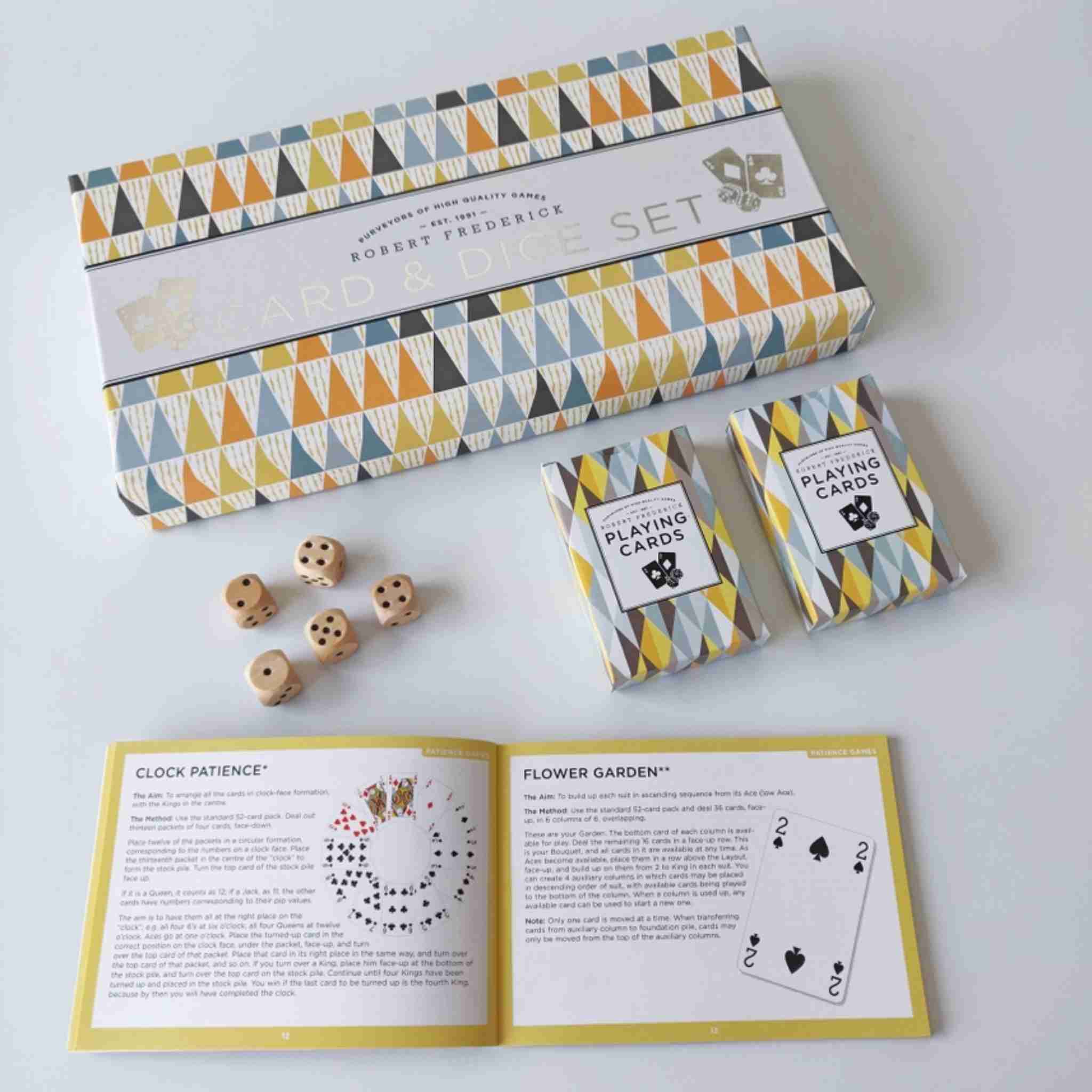 Playing card set with geometric patterned box, cards, dice, and instructions on a white background