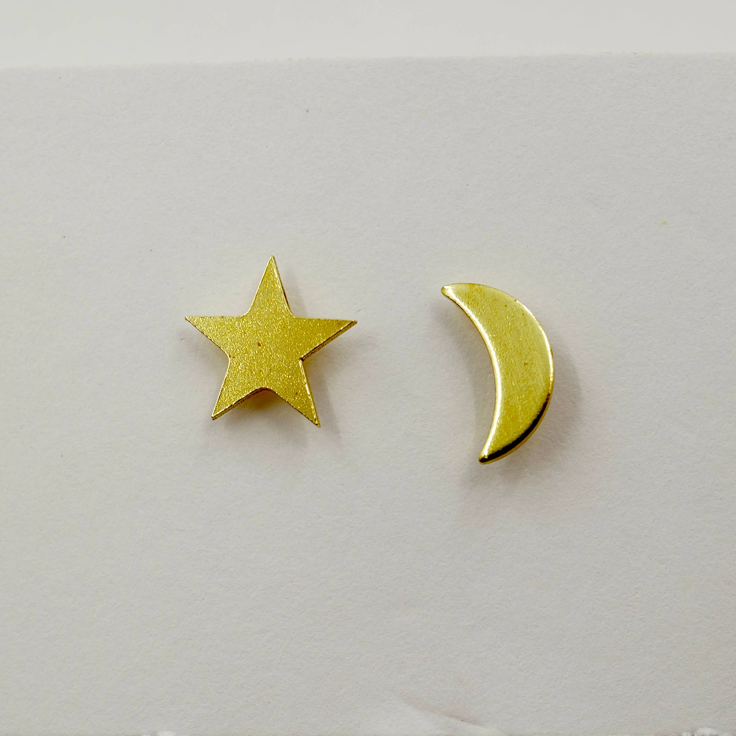 Gold star and moon earrings on a light gray background