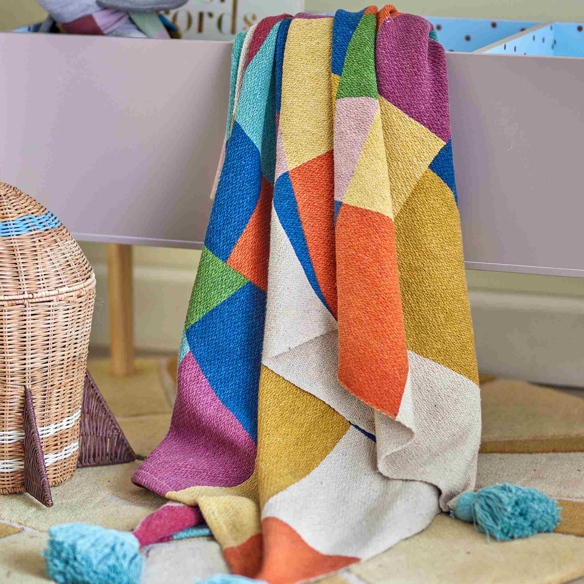 Colorful geometric-patterned blanket draped over a chair with a wicker basket 