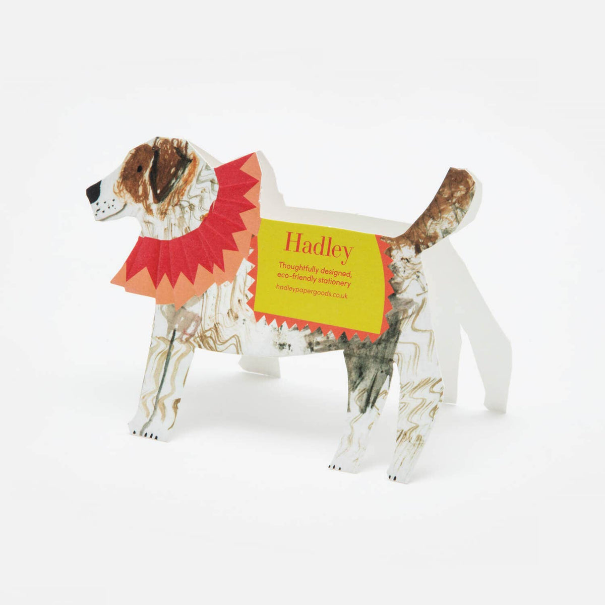 Cardboard dog model with a colorful collar and name tag on a white background