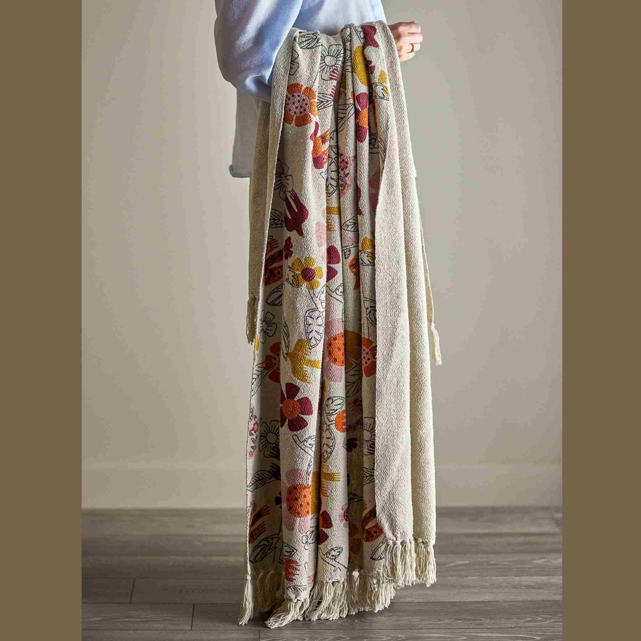 Person holding a floral-patterned blanket against a plain background