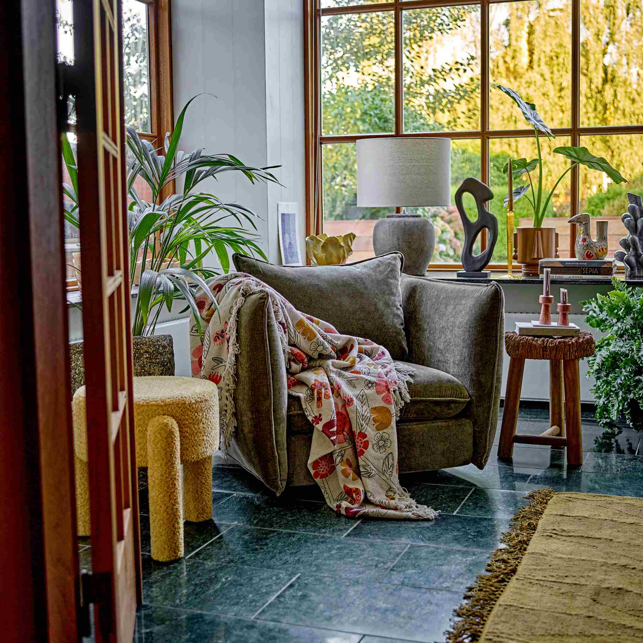 Cozy living room with a gray sofa, floral blanket, and decorative items.