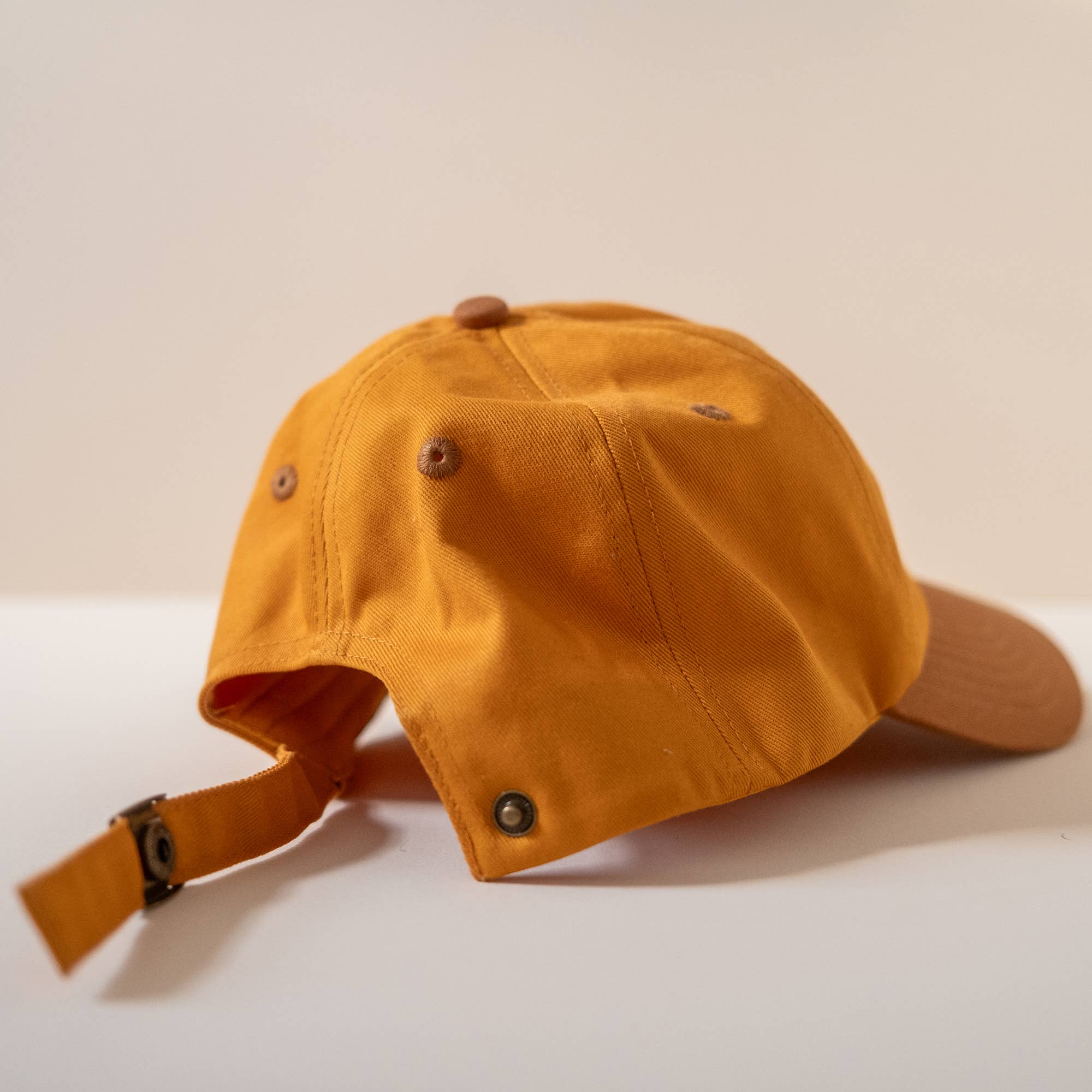 Orange cap with chin strap on a light beige background