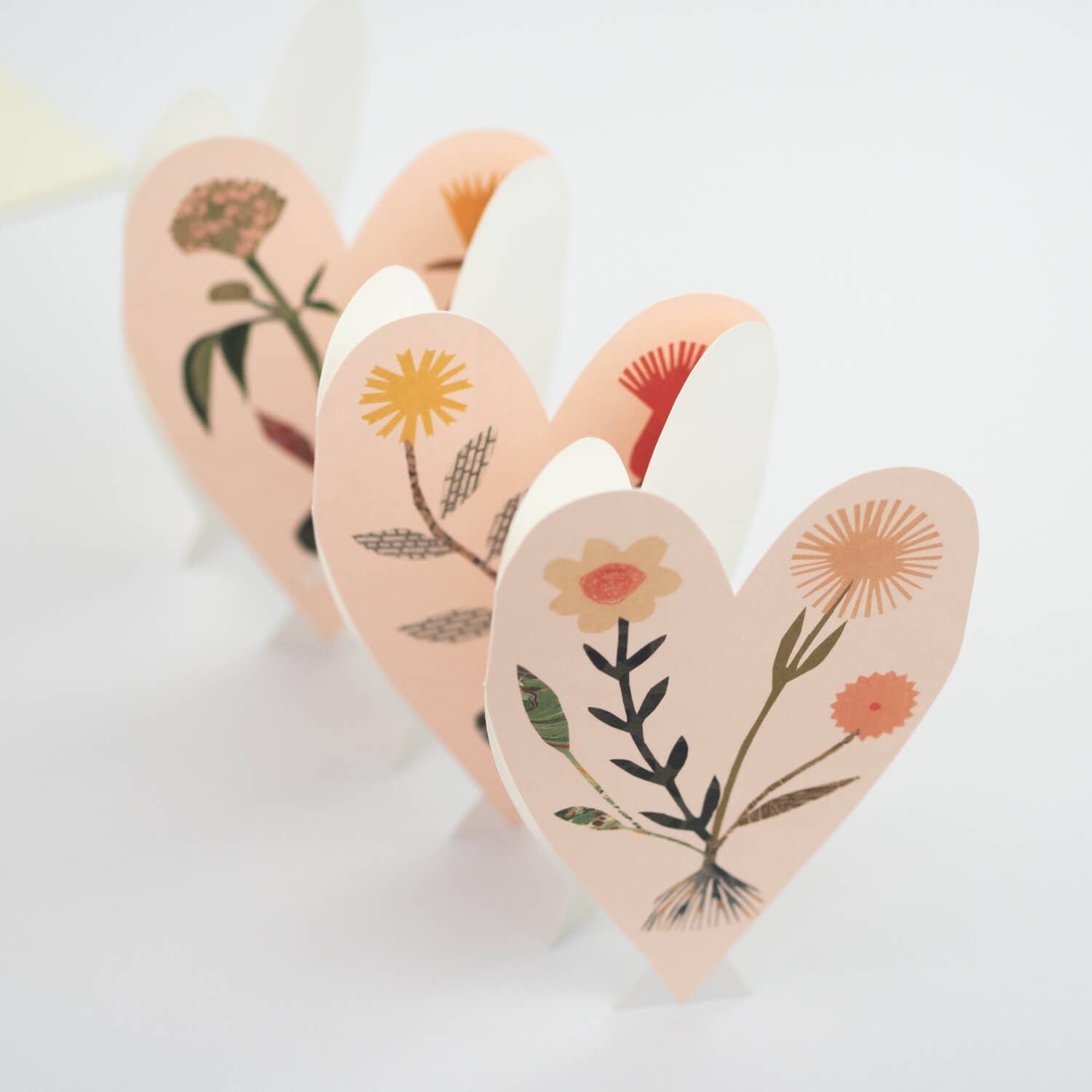 Set of heart-shaped wooden blocks with floral designs on a light background