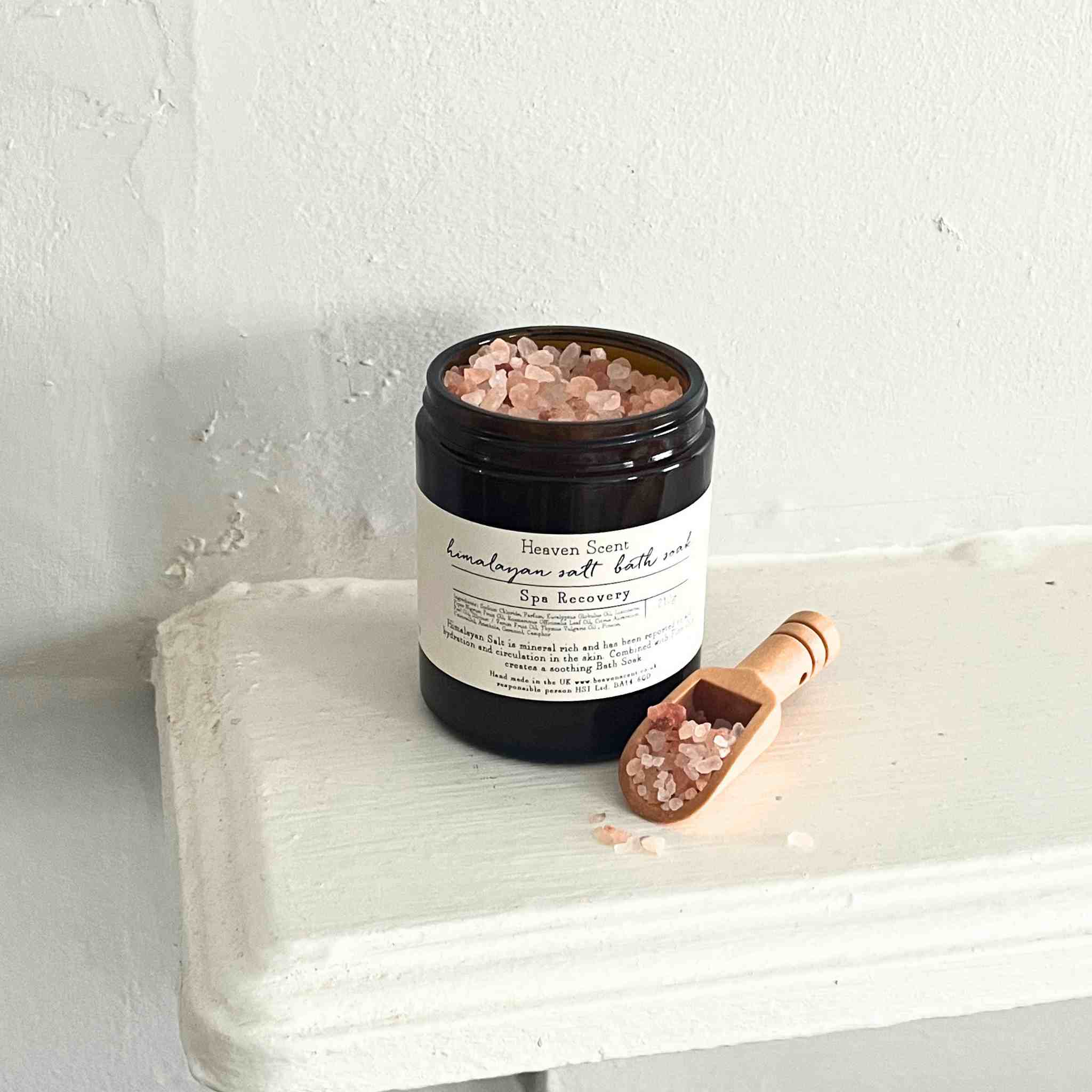 Jar of Himalayan salt bath soak with a scoop on a white surface