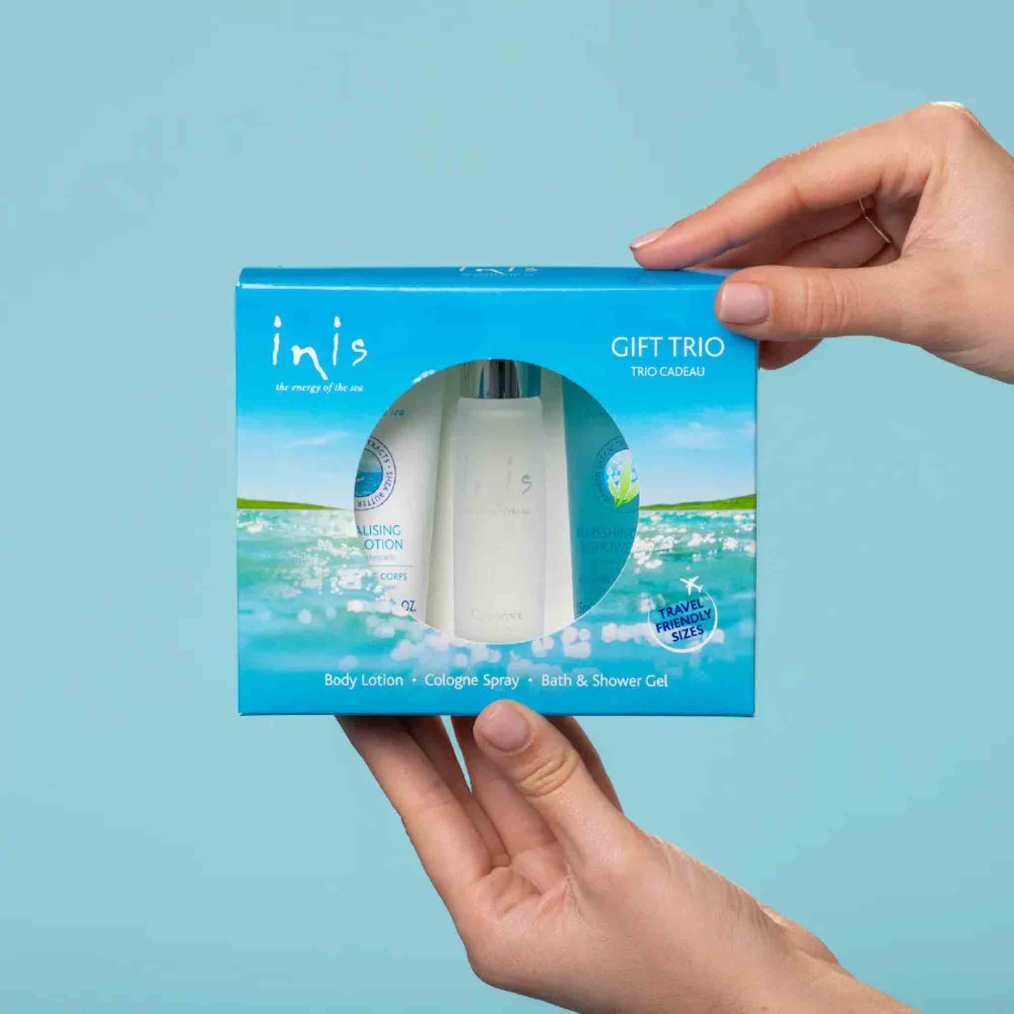 A person's hands holding a blue gift box containing a toiletry set from the brand inis. 