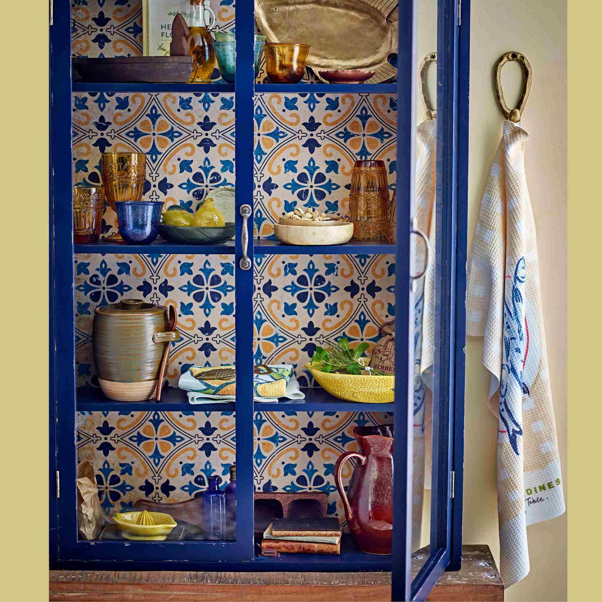 Decorative cabinet with colorful tile pattern and kitchen items in a kitchen setting.