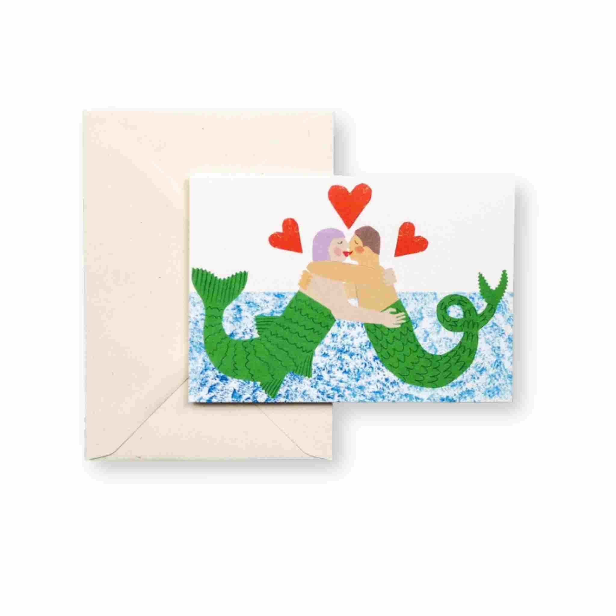 Greeting card with mermaid and human couple design, hearts, and envelope on a white background