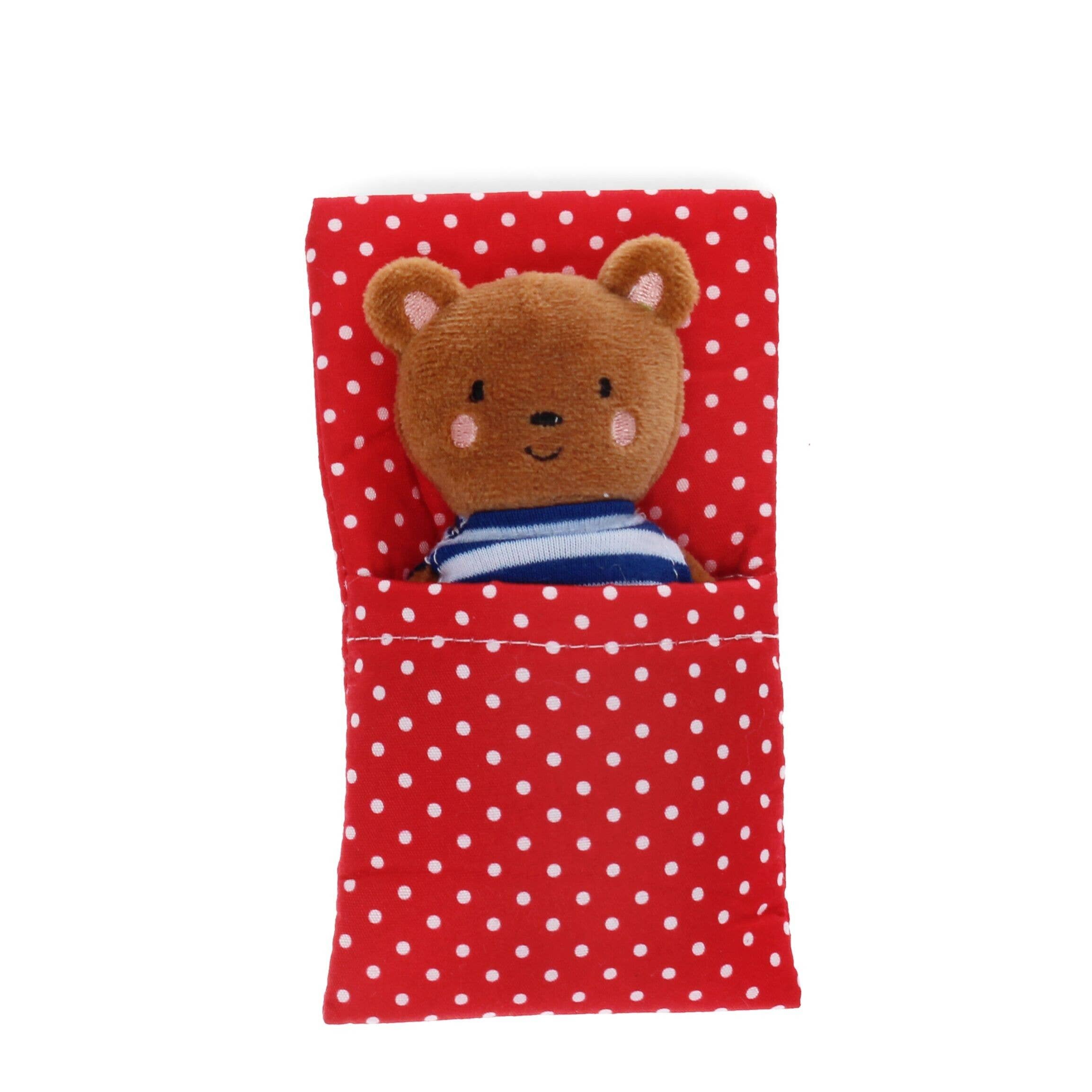 Plush bear toy in a red polka dot bag on a white background