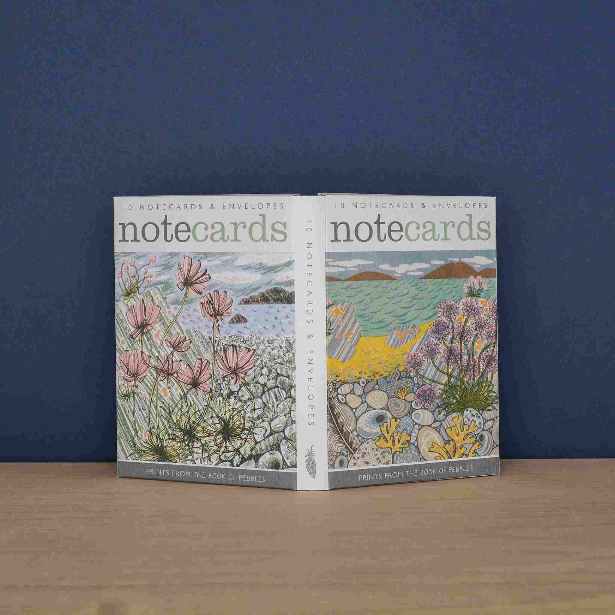 Set of notecards with floral designs on a wooden surface and blue wall background