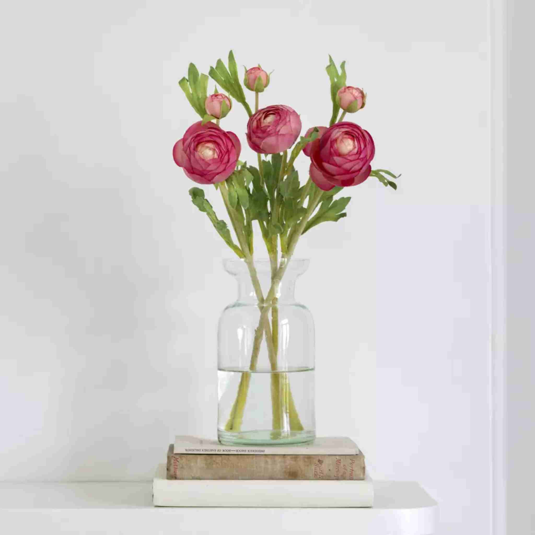 Clear glass vase with pink flowers on a white surface
