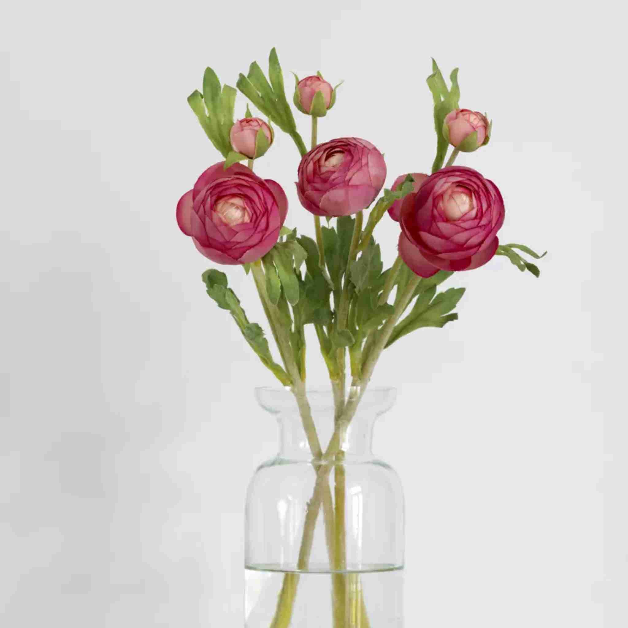 Clear glass vase with pink flowers on a light gray background