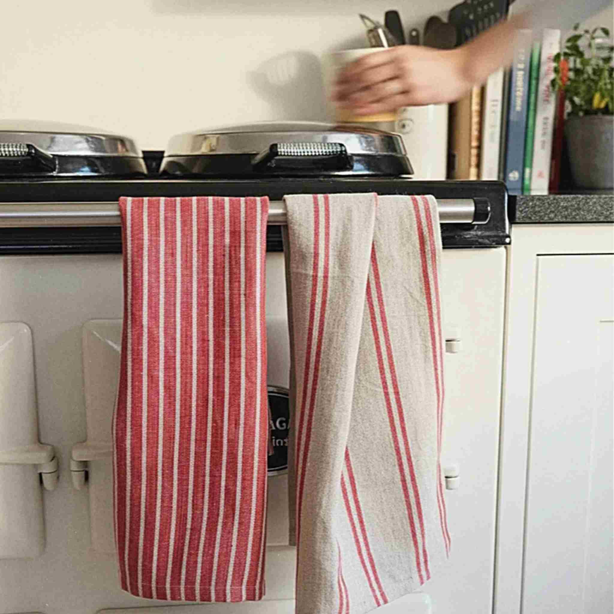 Red and white striped kitchen towels hanging on a stove handle in a kitchen.
