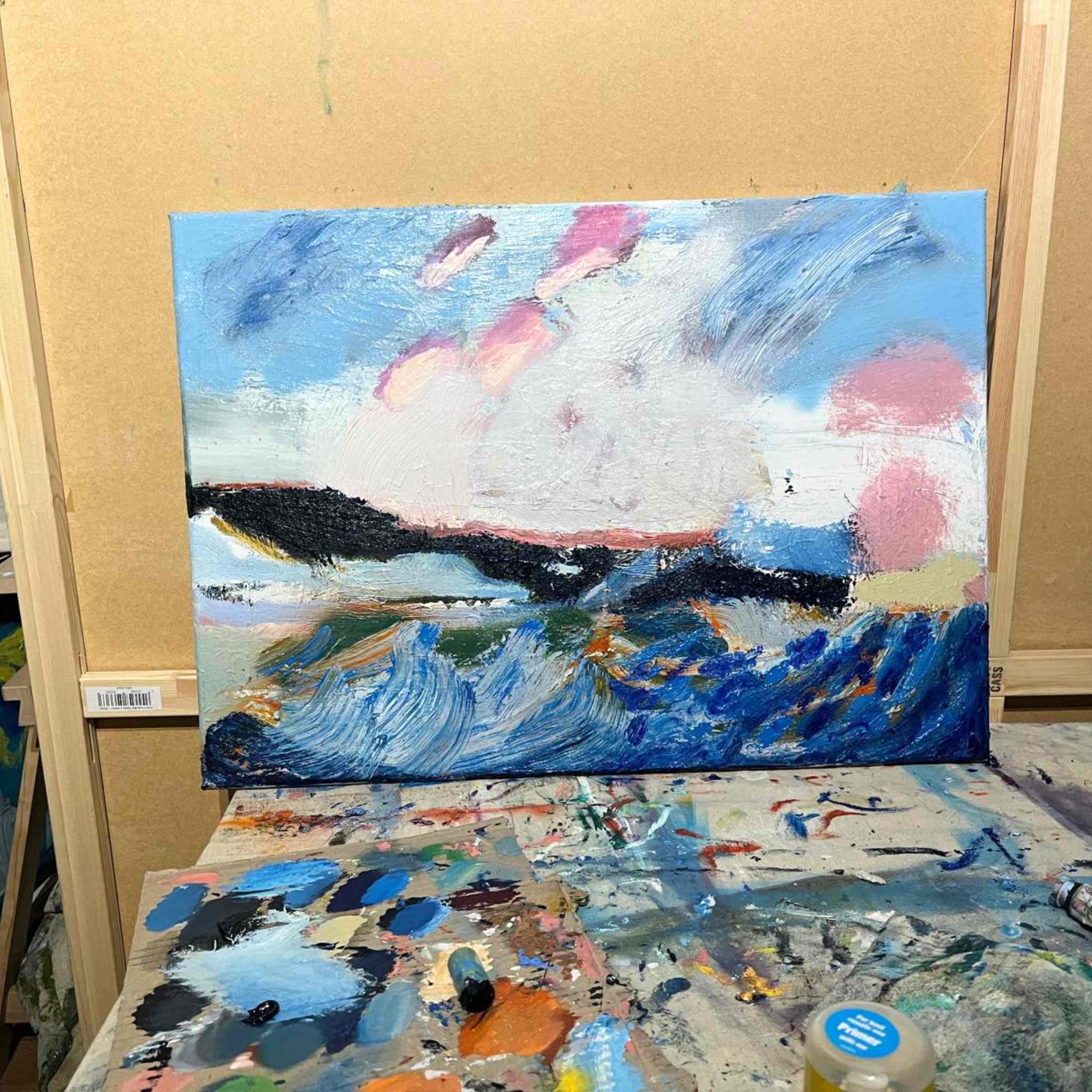 Abstract painting on a canvas with a palette and paint jar below