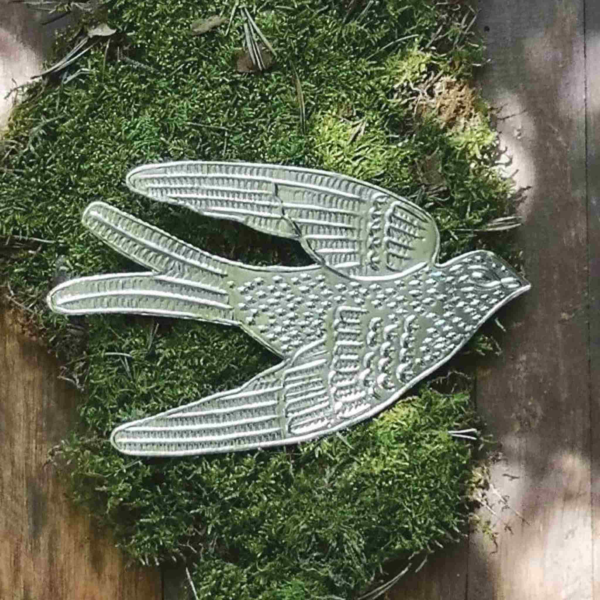 Decorative metal swallow bird on a mossy surface