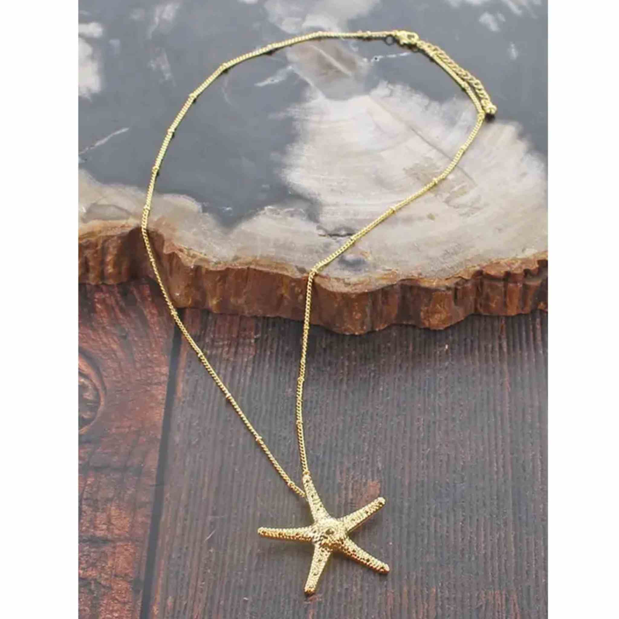 Gold starfish necklace on a wooden surface