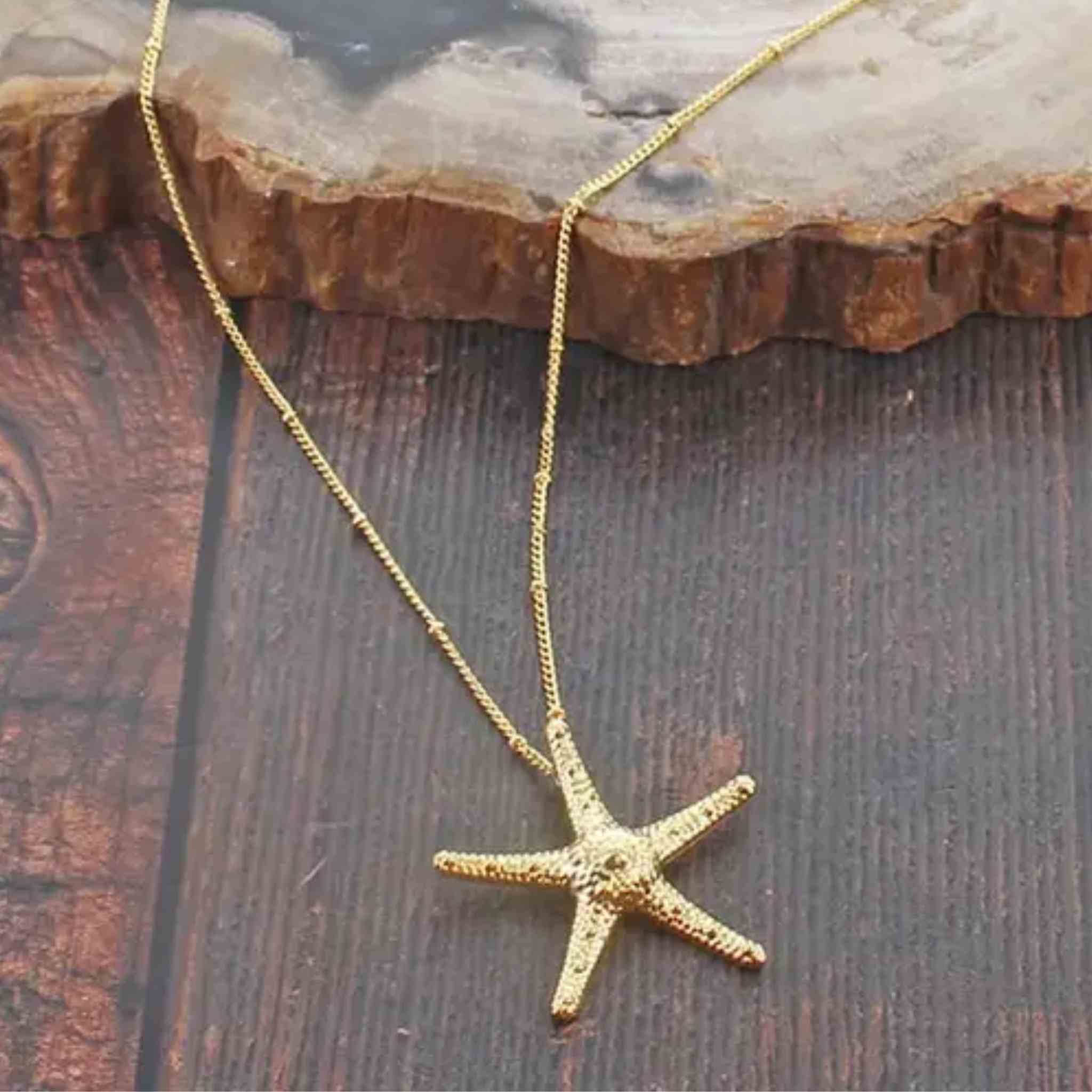 Gold starfish necklace on a wooden surface