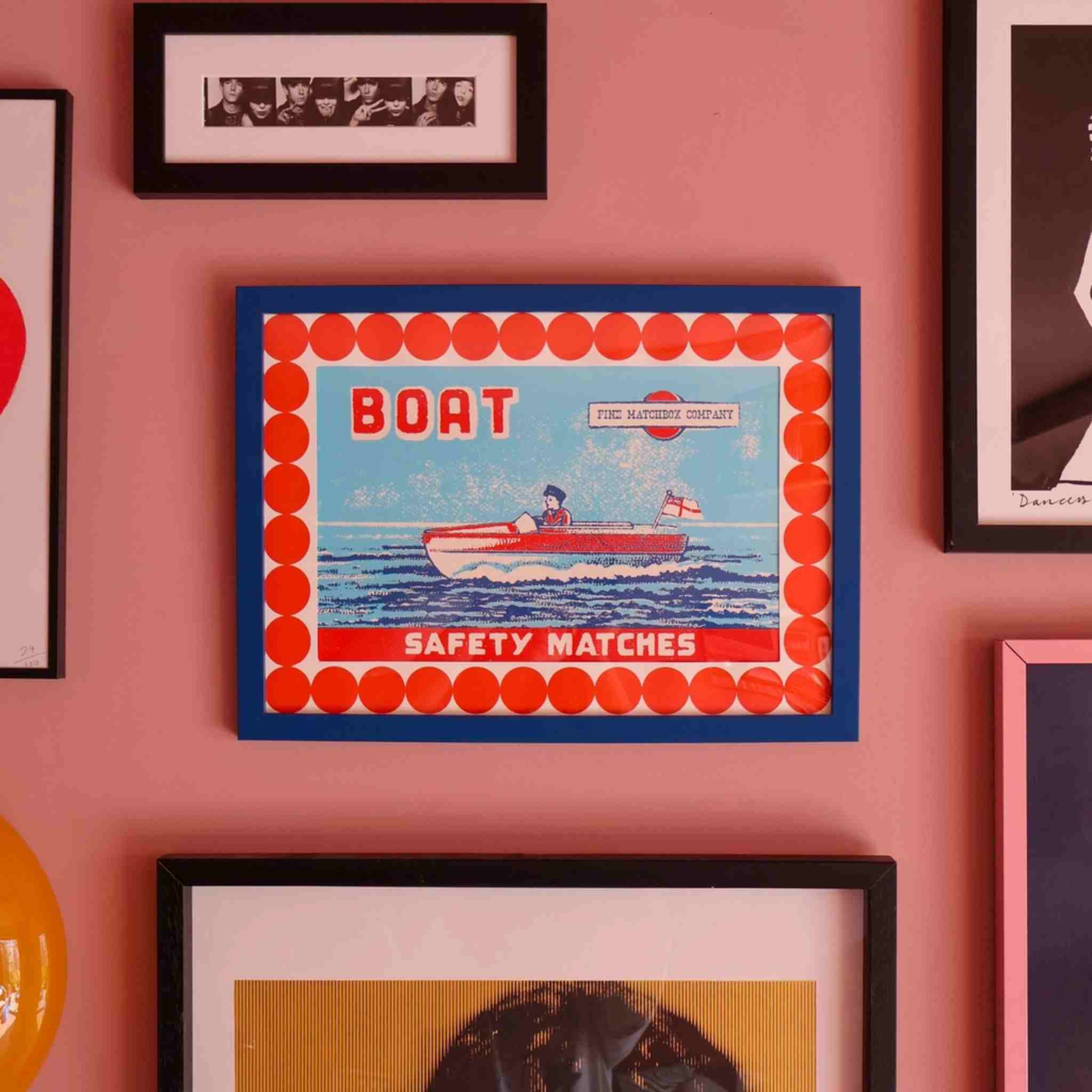 The Boat A3 Print, shown hang on a pink wall in blue frame