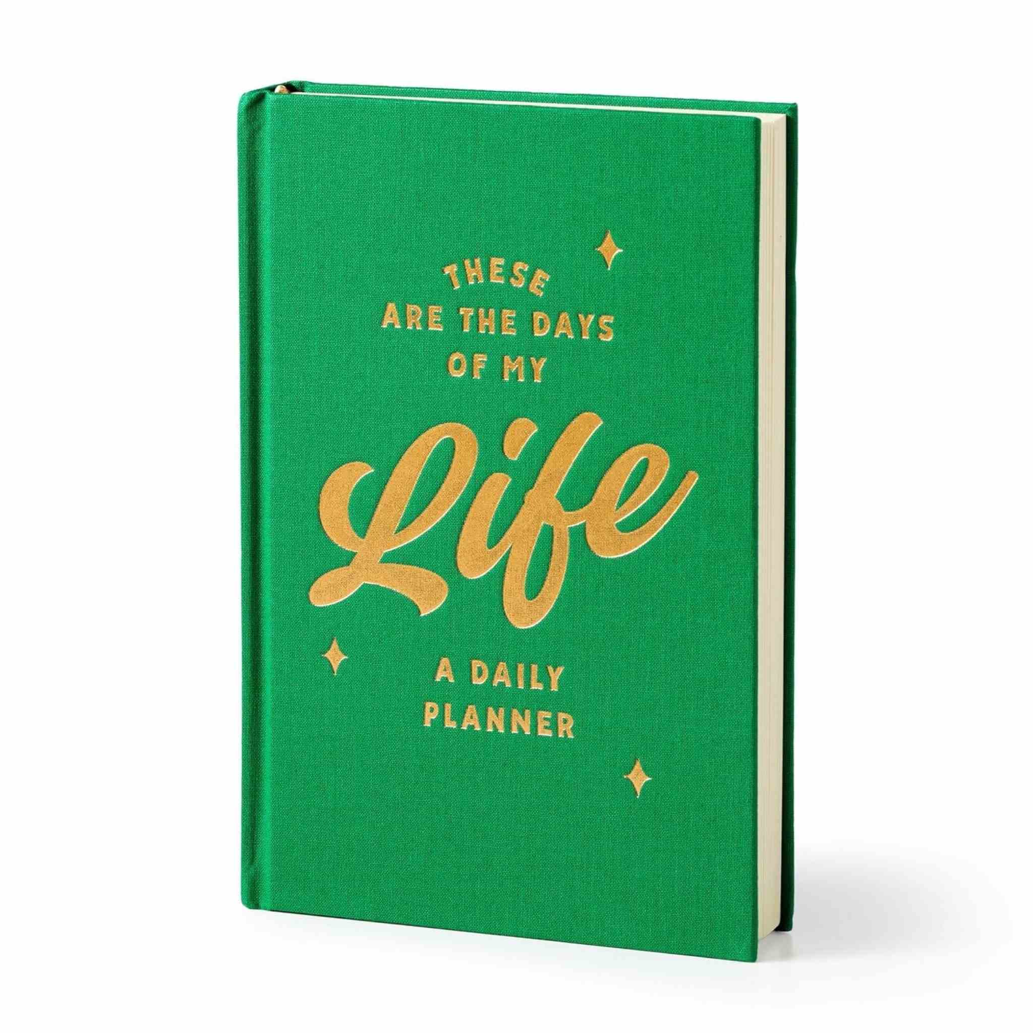 A green hardcover daily planner standing upright at a slight angle, featuring gold foil text that reads 'THESE ARE THE DAYS OF MY Life A DAILY PLANNER' with small gold stars on a white background.
