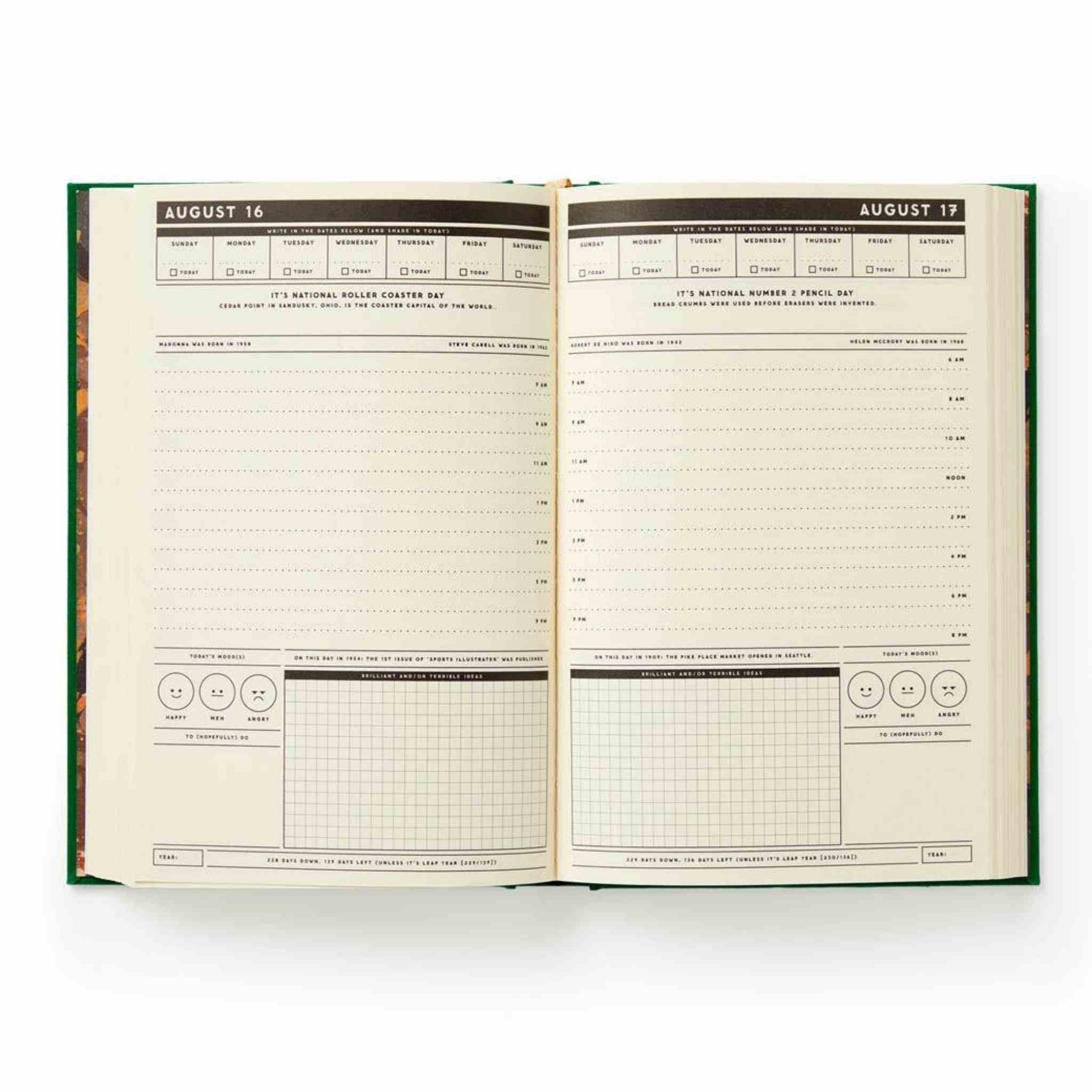 An open hardcover journal showing two interior pages with printed daily planning and habit-tracking layouts, photographed on a clean white background.