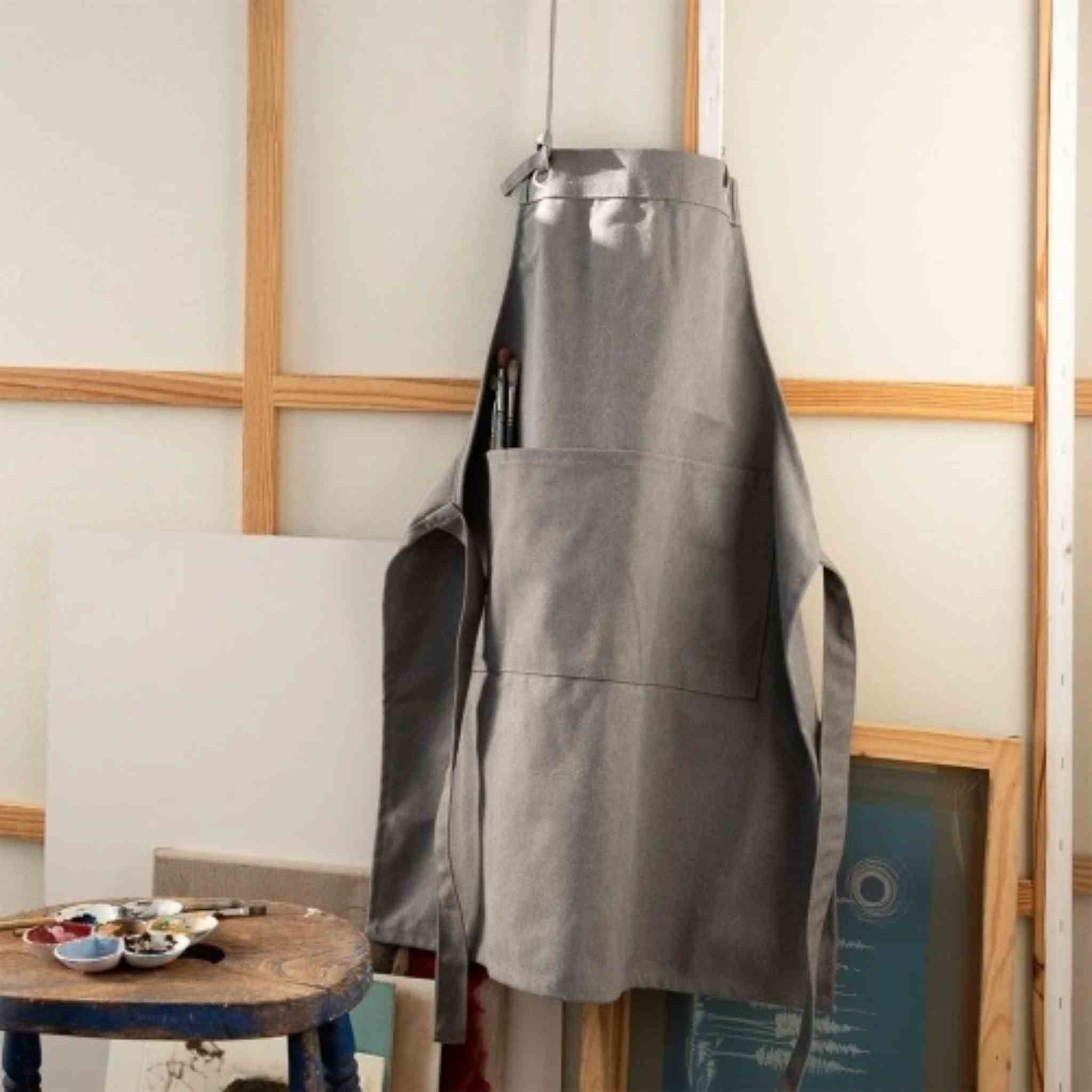 Gray apron hanging on a wooden frame with a neutral background