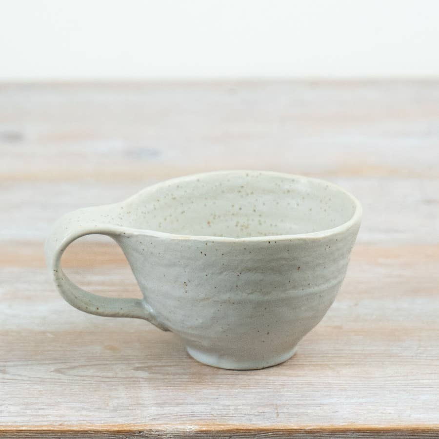 Speckled gray ceramic mug on a wooden surface with a light background