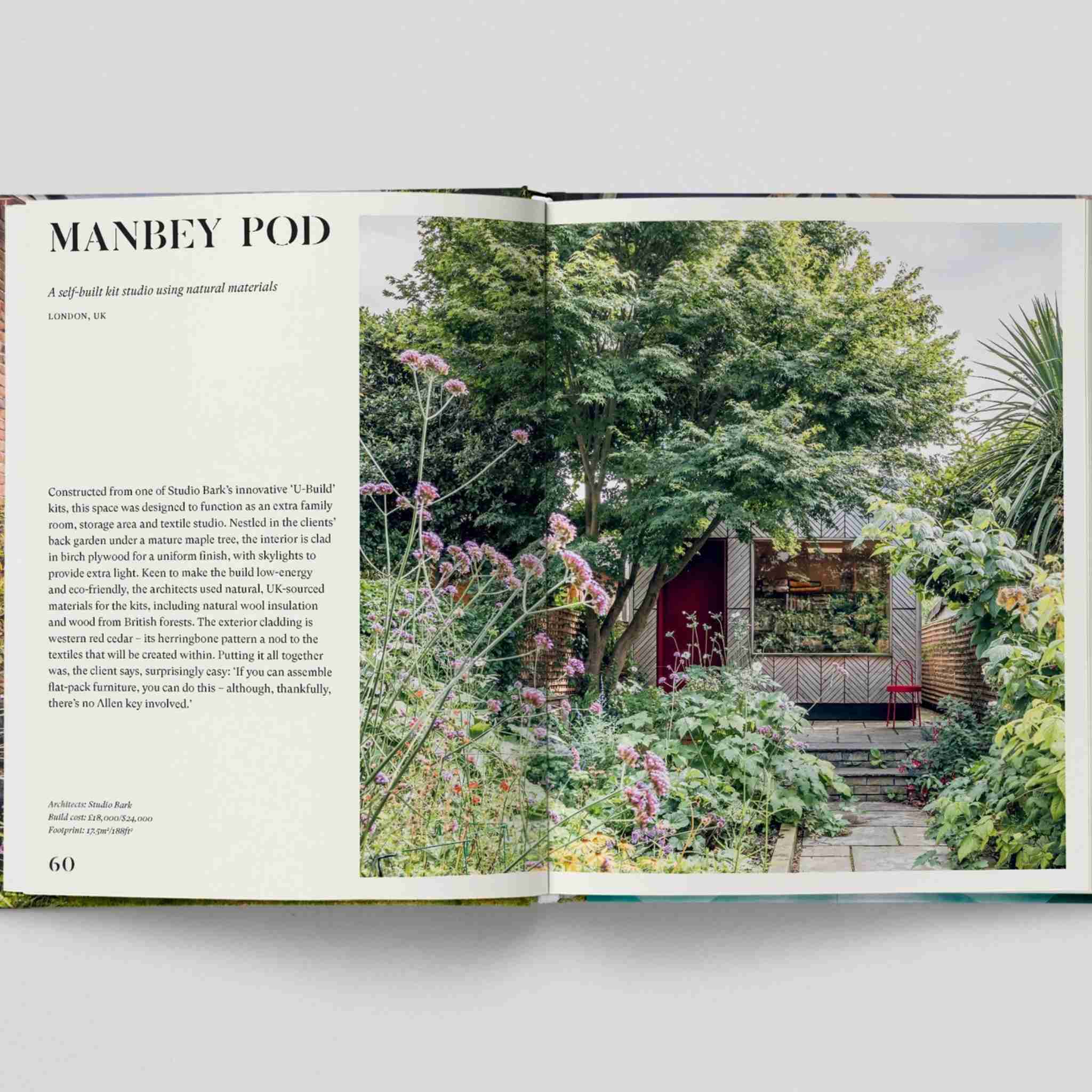 Open book showing a garden scene with a red shed and greenery.