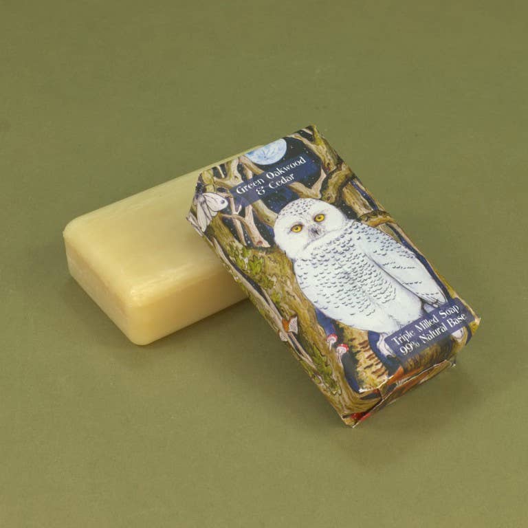 A bar of soap in its printed paper wrapper, features an illustration of a snowy owl on a tree trunk.