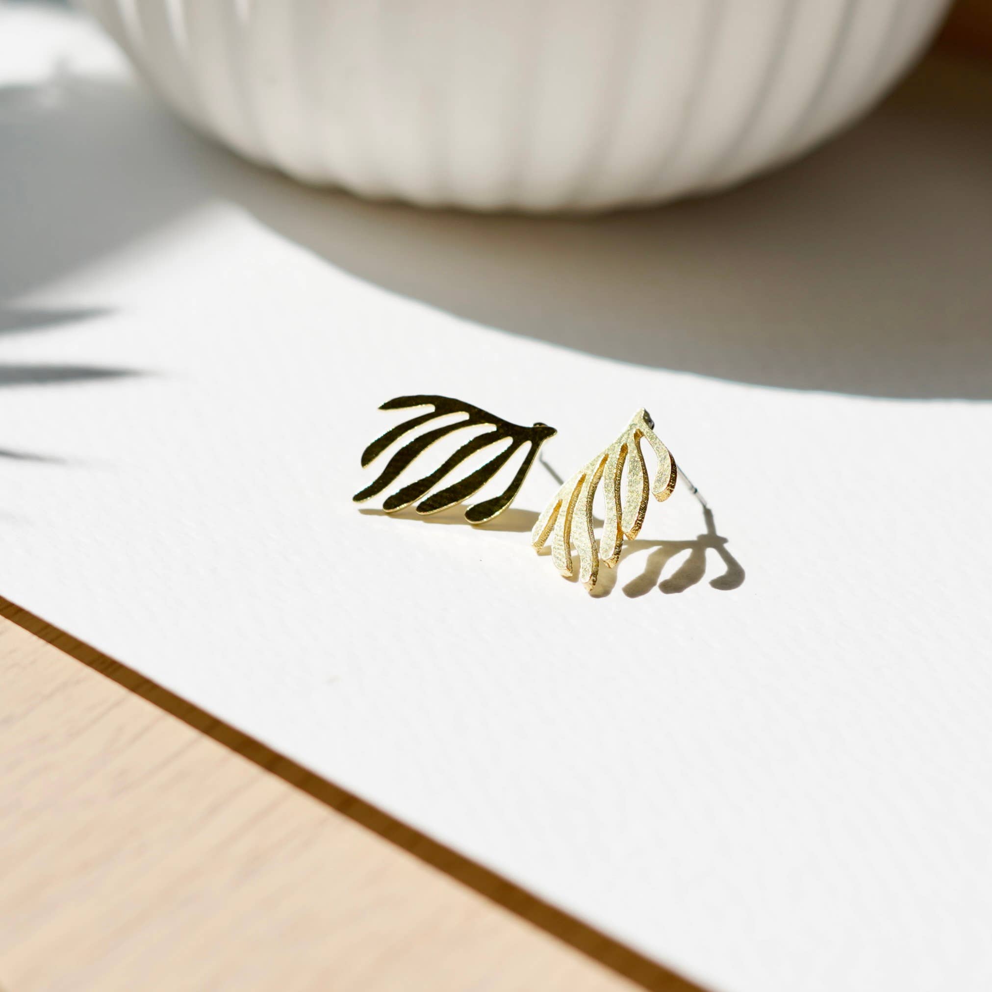 Gold earrings on a white surface with a blurred background