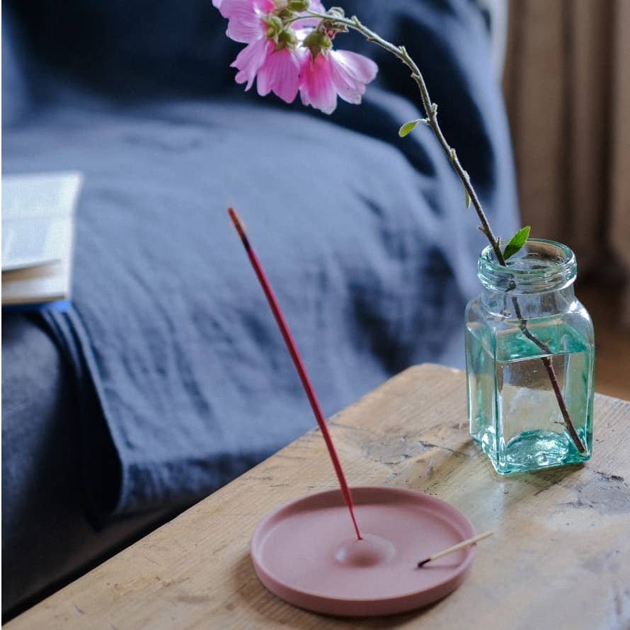 ceramic incense holder on a table with a flower in a jar